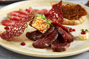 Meat appetizer in beige ceramic plate