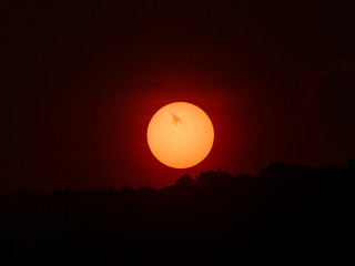 Sun hidden behind the clouds and mountains (Sunset).