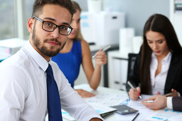 Handsome smiling bearded clerk man wearing glasses look in camera office portrait group of colleagues in background. Human resource modern training course strategy consult concept