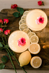 Two alcoholic beverages garnished with flowers and lemons in a pretty glassware