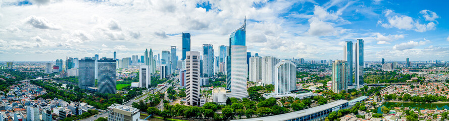 Aerial View of Jakarta Downtown Skyline with High-Rise Buildings With White Clouds and Blue Sky,...