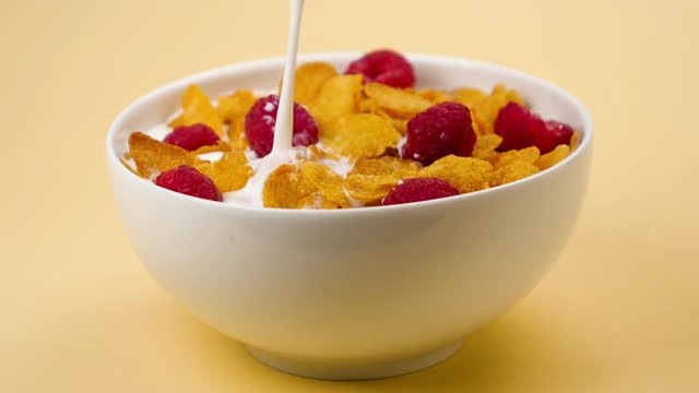 cornflakes with raspberries and milk pouring- slow motion