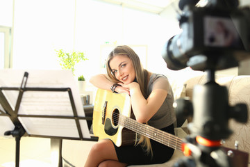 Fototapeta na wymiar Pretty Blogger Creating Musical Video Workshop. Education and Entertainment Vlog Content. Beautiful Person Fold Hands on Acoustic Guitar. Smiling Musician Playing at Leisure Recording Podcast