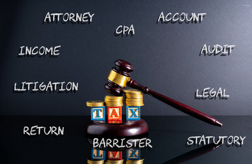 Gavel hammer and stacking coins and tax letter cube with low light view.