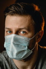 A man in a protective mask looks at the camera. Virus protection, self-isolation.