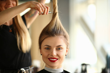 Hairdresser Holding Scissors on Smiling Woman Hair. Hairstylist Cutting Ponytail of Blonde Woman. Female with Red Lips Getting Hairstyle in Professional Beauty Salon Looking at Camera Photography