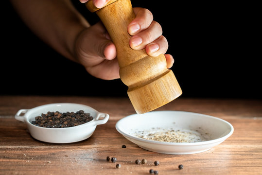 Granos de pimienta negra reci&eacute;n molida y granos enteros de pimienta negra en una plato de ceramica blanca