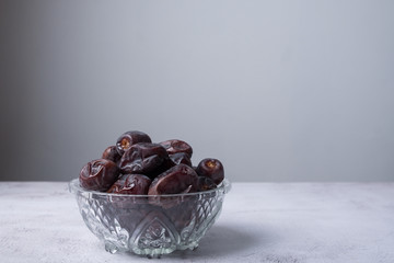 isolated sweet dates inside glass bowl with white background. close up shot with selective focus on foreground