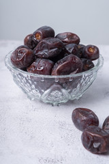 isolated sweet dates inside glass bowl with white background. close up shot with selective focus on foreground