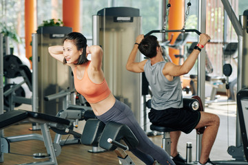 Fototapeta premium Smiling young Vietnamese woman doing hyperextension with hands behind her back