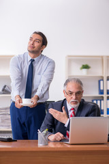 Old boss and young male employee in the office