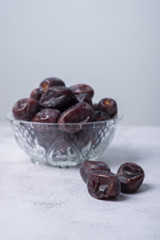 isolated sweet dates inside glass bowl with white background. close up shot with selective focus on foreground