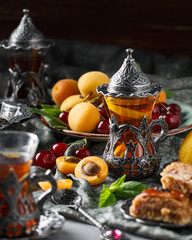 Fototapeta na wymiar tea armud in Turkish style with lemon. served on a silk tablecloth with baklava and fruit-cherries and apricots