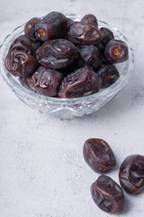 isolated sweet dates inside glass bowl with white background. close up shot with selective focus on foreground