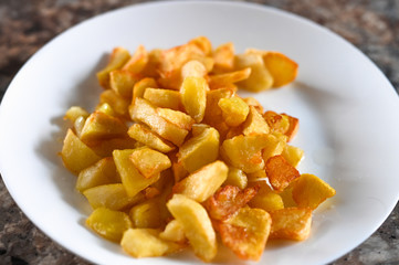 fried golden potatoes on a white plate. Fried potato wedges