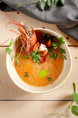 Tom yum soup in beige ceramic bowl top view