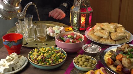 The Islamic holiday of Eid ul-Fitr marks the end of the Islamic fasting of the month of Ramadan. Traditional Eastern food and meal on the table. Muslim family eats together at home