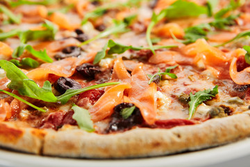 Sliced pizza with salmon, calamata olives and sun dried tomatoes