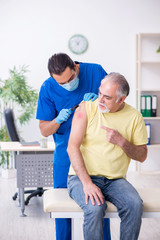 Obraz premium Ranny starzec odwiedzający traumatologa młodego mężczyznę