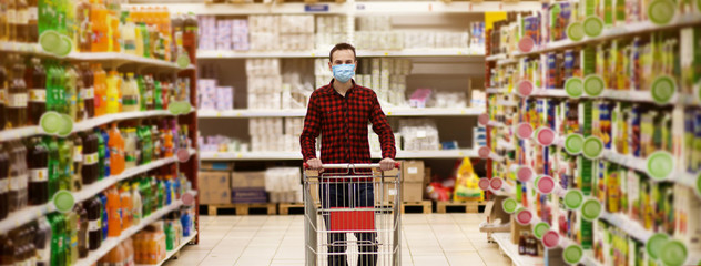 Man in protective mask shopping in supermarket pushing trolley during epidemic
