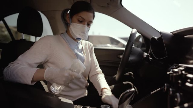 Car owner disinfecting vehicle with alcohol based sanitizing solution spray.Touched surfaces sanitation.Coronavirus COVID-19 spread prevention.Cross-contamination.Steering wheel disinfection