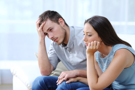 Sad worried couple complaining on a couch at home