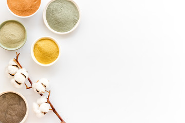 Yellow, red, white, blue and black cosmetic clay on white table top view copy space