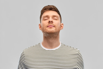 wellness and people concept - happy young man in striped t-shirt breathing over grey background - obrazy, fototapety, plakaty