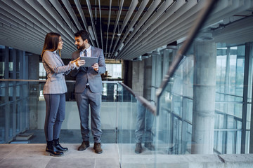 Fototapeta premium Two colleagues from successful corporate company standing in building in construction process and chatting. Man holding tablet.