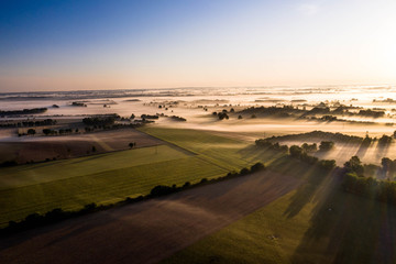 Aerial view of fields and trees under with fog