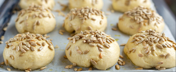 Raw dough balls sprinkled with seeds. Cooking homemade buns. Close-up, selective focus