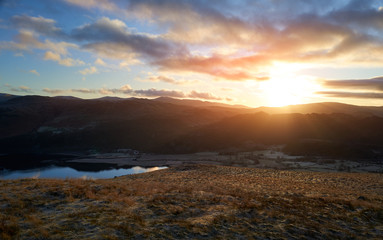 A bright orange sunny winters morning sunrise over Derwent Water, Borrowdale from below Cat Bells in the Lake District, UK.