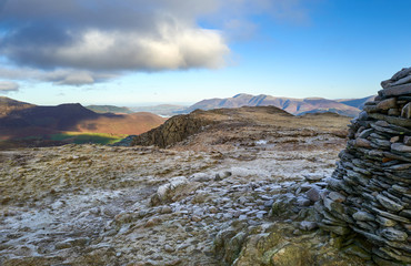 The frozen frost covered summit of High Spy in the Derwent Fells on a cold winters morning with Causey Pike in the distance in the Lake District.