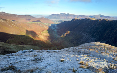 Sunrise on top of Dale Head with the valley of Newlands Beck below surrounded by High Crags, Maiden Moor & High Spy, the Derwent Fells in the winter mountains of the Lake District, UK.