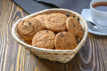 oatmeal cookies with chocolate chips in a basket on a wooden table