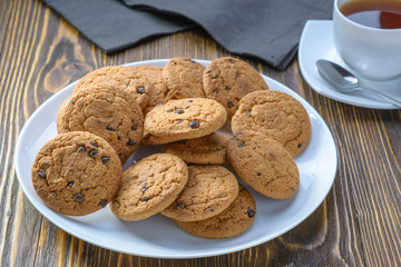 oatmeal cookies with chocolate chips on a white dish on a wooden table