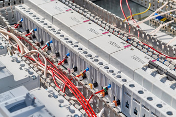 Red electrical wires are connected to modular contactors or starters in the electrical Cabinet. The wires and cables are laid in the cable channel. Professional production of electrical cabinets.