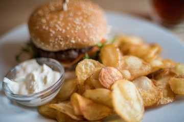 Close up of burger and french fries with sauce served on a plate