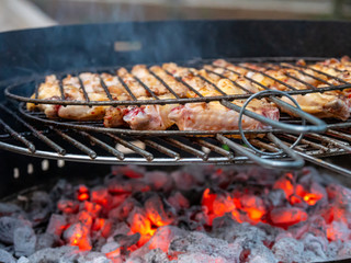 Grilled chicken legs on the flaming barbeque grill.