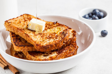 French toasts with berries and butter in white plate.