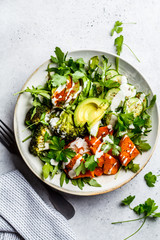 Baked sweet potato, broccoli and avocado salad bowl with tahini dressing, top view. Vegan food concept.