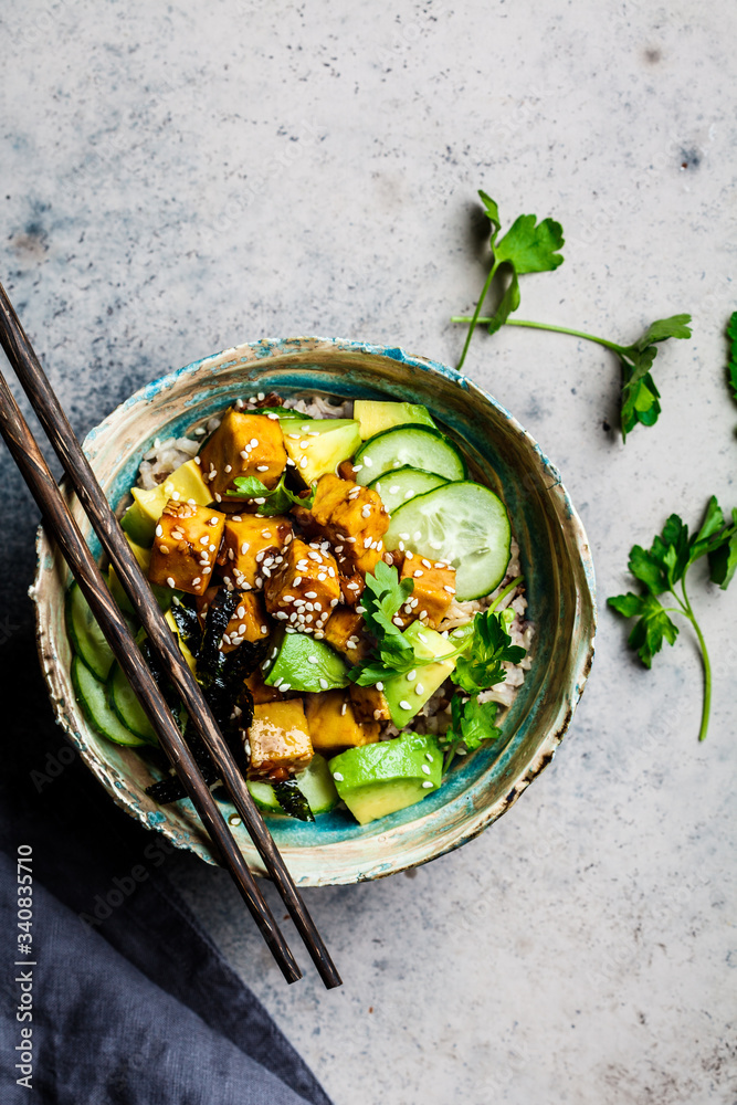 Canvas Prints Vegan tofu poke bowl with rice, cucumber, avocado and nori, gray background, top view.