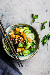 Vegan tofu poke bowl with rice, cucumber, avocado and nori, gray background, top view.