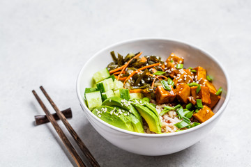Vegan ahi poke bowl with tofu, rice, seaweed, avocado and cucumber, white background.