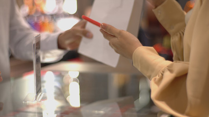 An upwardly mobile Asian Muslim woman using a mobile phone - smartwatch to pay for a product at a sale terminal with nfc identification payment for verification and authentication