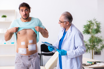 Injured young man visiting experienced male doctor