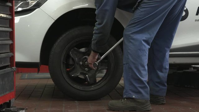 Closeup - mechanic screws on car tires. Tighten the wheel hub with a ratchet
