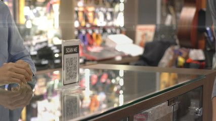 An upwardly mobile Asian Muslim man using a mobile phone - smartwatch to pay for a product at a sale terminal with nfc identification payment for verification and authentication