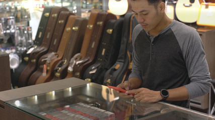 An upwardly mobile Asian Muslim man using a mobile phone - smartwatch to pay for a product at a sale terminal with nfc identification payment for verification and authentication