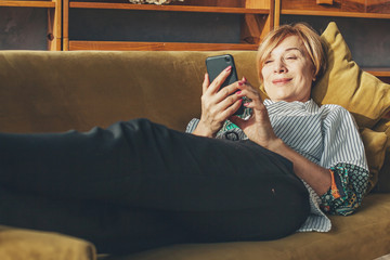 Senior lady with smart phone resting at home